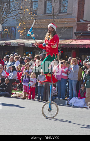 Asheville, North Carolina, Stati Uniti d'America - 17 Novembre 2012: un colorato giocoliere vestito come un elfo cavalca un monociclo intrattiene i bambini e Foto Stock