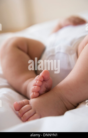 Piedi di bambina (2-5 mesi) giacenti nel letto Foto Stock