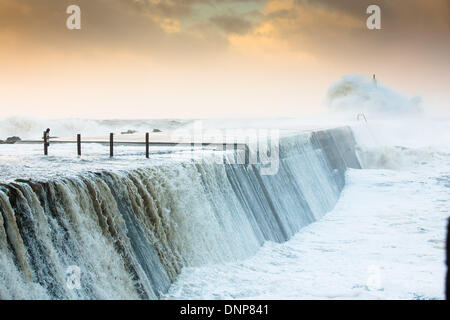 Aberystwyth, metà del Galles, UK. Il 3 gennaio 2014. Venti forti e una marea di primavera onde causare alla pastella il West Wales coast. La promenade a Aberystwyth è stata chiusa al pubblico come onde tore sopra la parete del mare, rompendo le difese del mare e la diffusione di detriti su una vasta area. La polizia e le guardie costiere cordoned-off del nord e del sud le passeggiate ad alta marea e un incendio del motore a filamento è diventato. Credito: atgof.co/Alamy Live News Foto Stock