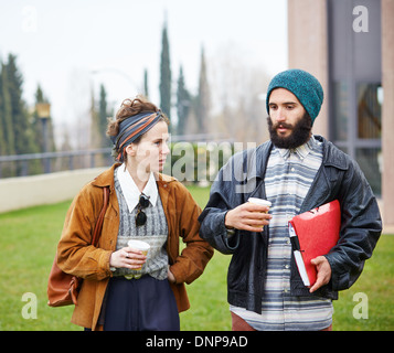 Hipster paio di parlare e di bere il caffè per andare al campus universitario Foto Stock