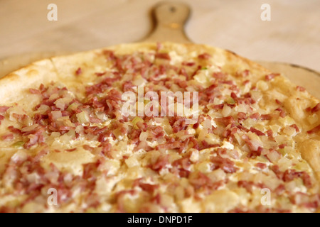 Tarte flambée (Flammkuchen) viene servita su una tavola di legno in un ristorante bavarese. Foto Stock