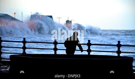 Porthcawl, Wales, Regno Unito . 03 gen 2014. Un uomo le lotte per camminare attraverso la forza di tempesta si snoda su Porthcawl esplanade, South Wales, Regno Unito, come eccezionalmente alte maree surge dietro di lui. Credito: Tom Guy/Alamy Live News Foto Stock