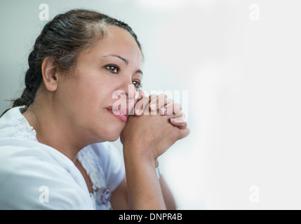 Contemplativa donna ispanica contro uno sfondo luminoso Foto Stock