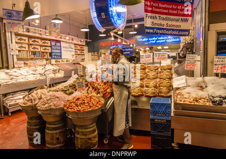 Fish monger disponendo crab gambe in uno stallo del mercato Pike Place Market di Seattle, Washington, Stati Uniti d'America Foto Stock