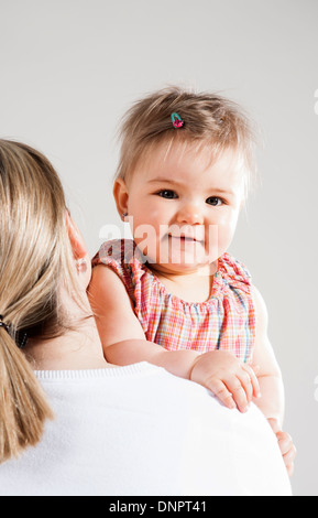 Ritratto di bambina cerca su madre della spalla, Studio Shot Foto Stock