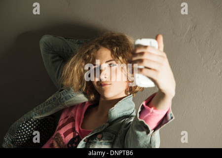 Ragazza adolescente tenendo Autoritratto con la fotocamera del telefono, Studio Shot Foto Stock