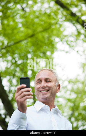 Close-up di uomo maturo guardando lo smartphone nel parco, Mannheim, Germania Foto Stock