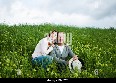 Ritratto di Coppia matura seduta nel campo di erba, abbracciando, Germania Foto Stock
