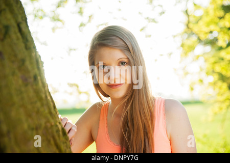 Ritratto di giovane donna in piedi accanto al tronco di albero, Germania Foto Stock