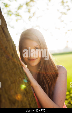 Ritratto di giovane donna in piedi accanto al tronco di albero, Germania Foto Stock