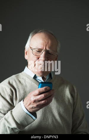 Uomo anziano utilizzando il cellulare in Studio Foto Stock