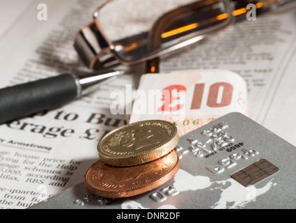 Bicchieri, monete, carte di credito e banconote sul giornale.Macro shot Foto Stock