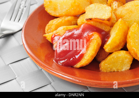 Ingrandimento di una piastra con tipico spagnolo patatas bianche, patate fritte con una salsa calda Foto Stock