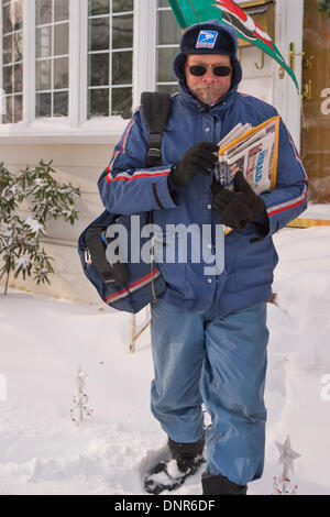 Merrick, New York, Stati Uniti Il 3 gennaio 2014. Un gestore di posta elettronica per il Servizio Postale degli Stati Uniti i fornitori del servizio universale la Posta recapita a casa come un pericoloso Deep Freeze si assesta dopo un blizzard oggetto di dumping 6-12 cm di neve su Long Island. Il range di temperatura è 13 a 18 gradi Fahrenheit (-11° a -8° Celsius), con presenza di raffiche di vento fino a 45 km/h. Wind chill fattori la rendono tra 5° F a -10° F (-15° a -23° C), con un record di bassi previsto in notturna. Credito: Ann e Parry/Alamy Live News Foto Stock