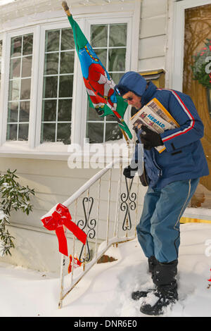 Merrick, New York, Stati Uniti Il 3 gennaio 2014. Un gestore di posta elettronica per il Servizio Postale degli Stati Uniti USPS cammina giù un unshoveled fasi di front stoop per recapitare la posta come una pericolosa Deep Freeze si assesta dopo un blizzard oggetto di dumping 6-12 cm di neve su Long Island. Il range di temperatura è 13 a 18 gradi Fahrenheit (-11° a -8° Celsius), con presenza di raffiche di vento fino a 45 km/h. Wind chill fattori la rendono tra 5° F a -10° F (-15° a -23° C), con un record di bassi previsto in notturna. Credito: Ann e Parry/Alamy Live News Foto Stock