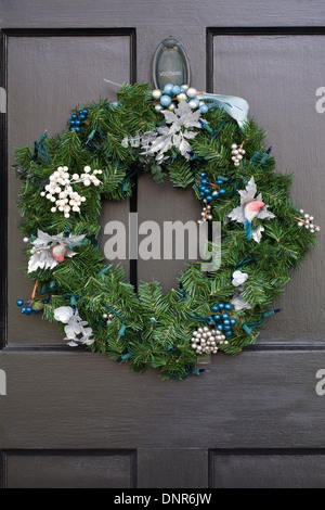 Decorativa ghirlanda di Natale appeso al buio su un porta anteriore. Foto Stock