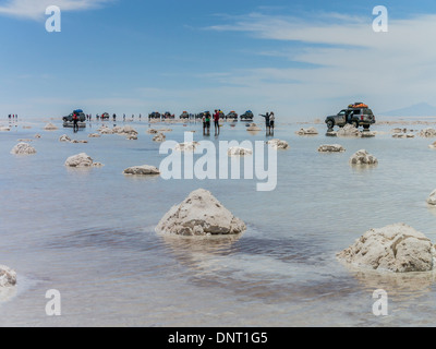 Turisti e quattro ruote motrici interrompere di prendere nel singolare interazione dei riflessi dall'acqua sul Salar de Uyuni. Foto Stock