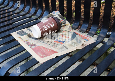 Svuotare il McDonald McCafé carta tazza di caffè e un giornale bagnato su una panchina nel parco. Foto Stock