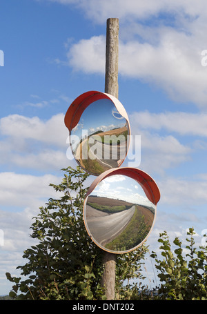 Due strade convesse Specchi di sicurezza sul posto di legno su un ingresso nascosto su un rettilineo di strada di campagna Foto Stock