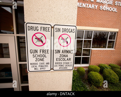 Al di fuori di una scuola elementare, un segno in spagnolo e in inglese avvertenza i genitori, gli studenti e i visitatori è farmaco e la pistola libera Foto Stock