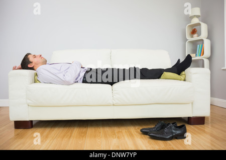 Imprenditore stanco di dormire sul divano nel soggiorno Foto Stock