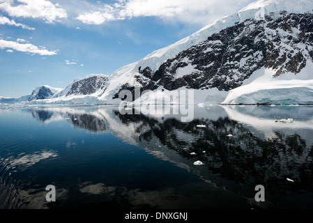Neko Harbour Mountains and Reflections Antartide // NEKO HARBOR, Antartide: Le montagne panoramiche ghiacciate e rocciose ricoperte di ghiaccio e neve a Neko Harbour sulla penisola Antartica si riflettono su acque calme e cristalline simili a specchi. Foto Stock