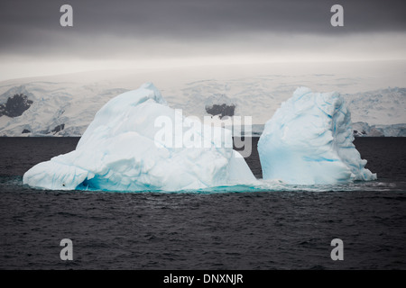 Antartide - Un iceberg galleggia in acque gelide del Curtis Bay sulla penisola antartica. Mentre le due sezioni separate appaiono sopra l'acqua, le sezioni sono collegate da un molto più grande a sezione singola sotto l'acqua. Foto Stock