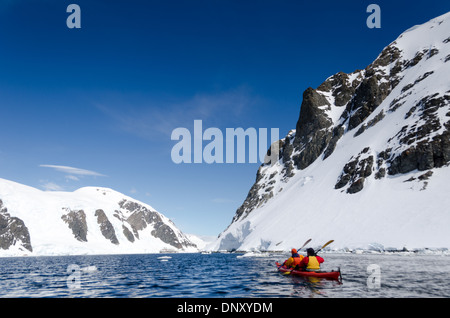 ISOLA CUVERVILLE, Antartide: I kayak si fermano per ammirare il paesaggio mozzafiato in una giornata limpida e soleggiata all'isola di Cuverville sulla penisola Antartica. Il paesaggio incontaminato di montagne innevate, ghiacciai e acque calme offre uno sfondo meraviglioso per questi avventurieri mentre esplorano uno dei luoghi più remoti e belli della Terra. Foto Stock