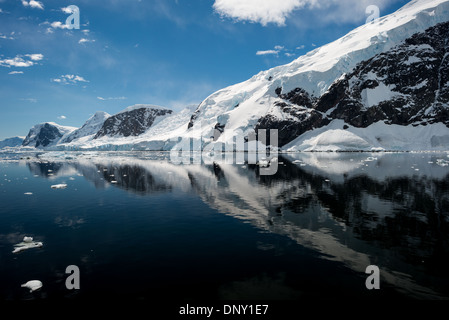 Neko Harbour Riflesso delle Montagne Ghiacciate Penisola Antartica Antartide | NEKO HARBOUR, Antartide — Le cime innevate sopra Neko Harbour si riflettono sulla superficie calma come uno specchio della baia di Andvord, un’insenatura simile a un fiordo sulla costa Danco della Terra di Graham. Uno sbarco qui è uno dei pochi luoghi in cui i turisti mettono piede sul continente antartico anziché su un’isola al largo. Il porto prende il nome dalla Neko, una nave fabbrica baleniere della Chr. Salvesen & Co. che qui ha gettato l’ancora tra il 1911 e il 1924. Foto Stock