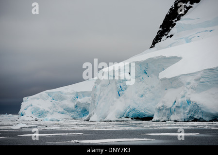 Antartide - un ghiacciaio di uno spesso strato di ghiaccio e neve scende gradualmente nel mare come esso fluisce giù per il fianco della montagna presso il canale di Lemaire in Antartide. Il Lemaire Channel è talvolta indicata come "Kodak Gap' in un cenno al suo famoso vedute panoramiche. Foto Stock