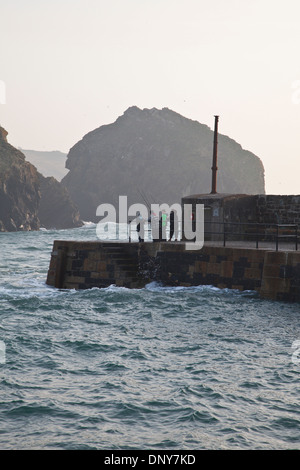 Mullion Cove Harbour, penisola di Lizard, Cornwall. Persone di pesca dalla fine del molo di pietra Foto Stock