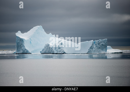 Antartide - Antartide Iceberg la sottile la colorazione si staglia contro le acque calme e cieli grigi vicino Galindez Island in Antartide. Foto Stock