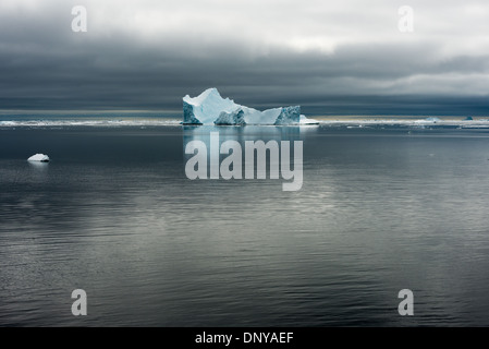 Antartide - Antartide Iceberg la sottile la colorazione si staglia contro le acque calme e cieli grigi vicino Galindez Island in Antartide. Foto Stock