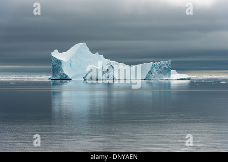 Antartide - Antartide Iceberg la sottile la colorazione si staglia contro le acque calme e cieli grigi vicino Galindez Island in Antartide. Foto Stock