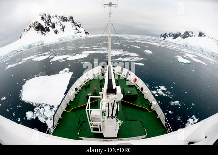 [Canale di Lemaire Antartide] [Penisola Antartica del Canale di LEMAIRE] [Penisola di Kiev] CANALE DI LEMAIRE, Antartide — una nave da spedizione rinforzata dal ghiaccio naviga attraverso placche sparse di ghiaccio marino nelle acque calme del Canale di Lemaire. Lo stretto passaggio lungo la penisola antartica, soprannominato "Kodak Gap", richiede navi appositamente progettate per gestire le diverse condizioni del ghiaccio mentre trasportano i visitatori attraverso questo percorso panoramico. Foto Stock