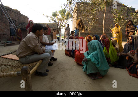 Mar 07, 2006; Anantpur village, Uttar-Pradesh, INDIA; UN CASHPOR micro-credito dipendente, Basant (uomo seduto con documenti, un centro Manager) raccoglie un deposito bancario, controlli dei clienti' partecipazione e dicsusses problemi sulla sua visita settimanale di un remoto villaggio dove un gruppo di clienti qualificati per i microcrediti. La donna seduta accanto a Basant è Subnam, il suo supervisore (Manager di Foto Stock