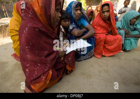 Mar 07, 2006; Anantpur village, Uttar-Pradesh, INDIA; UN CASHPOR micro-credito dipendente, Basant (uomo seduto con documenti, un centro Manager) raccoglie un deposito bancario, controlli dei clienti' partecipazione e dicsusses problemi sulla sua visita settimanale di un remoto villaggio dove un gruppo di clienti qualificati per i microcrediti. La donna seduta accanto a Basant è Subnam, il suo supervisore (Manager di Foto Stock