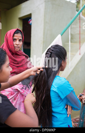 Rurale villaggio indiano ragazza adolescente avente i suoi capelli intrecciati. Andhra Pradesh, India Foto Stock