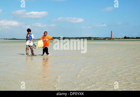 Apr 09, 2006; New Smyrna, FL, Stati Uniti d'America; Patrick Mayes, sinistra e Max Howard giocare nell'acqua chiara che copre un sandbar appena dentro il Ponce Inlet vicino a New Smyrna Beach. Il Ponce Inlet Lighthouse è in background. Credito: Foto di Willie Howard/Palm Beach post/ZUMA premere. (©) Copyright 2006 da Palm Beach post Foto Stock