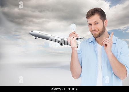 Immagine composita del modello affascinante tenendo una lampadina in mano destra Foto Stock