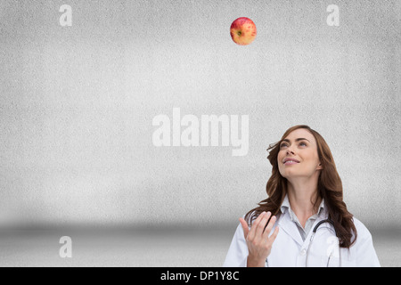 Immagine composita di felice medico gettando apple Foto Stock