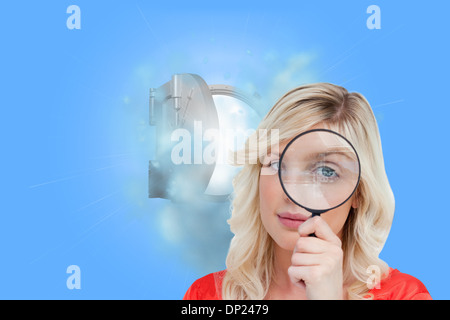 Immagine composita del biondo donna guardando attraverso una lente di ingrandimento Foto Stock