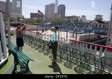 Maggio 23, 2006; New Orleans, LA, USA; un turista asiatico prende una foto di sua moglie tra le sedie vuote di rivestimento del mancorrente della Natchez Steamboat. Il Natchez è il solo dei New Orleans sulla Paddlewheeler attualmente in funzionamento, eppure si rende molte delle sue ore di lunghe crociere con solo il dieci percento della sua normale carico di passeggeri. Prima di Katrina, vi erano tre sulla Paddlewheeler aperto a t Foto Stock