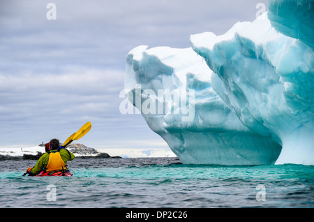 Antartide - Kayakers in un tandem Kayak scivolano passato un iceberg che è stato si inclina lentamente a rocce Hydrurga a due Hummock isola. La regione è nota come un preferito per leopard guarnizioni (Hydrurga leptonyx). Foto Stock