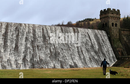 Il Peak District, Derbyshire, Regno Unito. Il 7 gennaio 2014. Dopo giorni di pioggia pesante, escursionisti sono sopraffatte da una parete d'acqua che trabocca dalla Derwent serbatoio sopra la diga Derwent nel Derbyshire Peak District. La diga è uno dei tre nella Derwent Vally che è stato reso famoso dalla Dambusters missioni di addestramento. Credito: Joanne Roberts/Alamy Live News Foto Stock