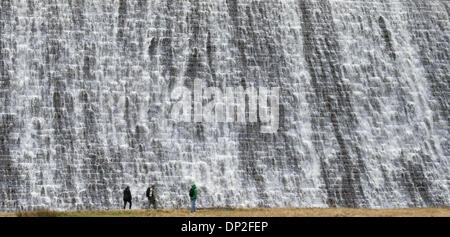 Il Peak District, Derbyshire, Regno Unito. Il 7 gennaio 2014. Dopo giorni di pioggia pesante, escursionisti sono sopraffatte da una parete d'acqua che trabocca dalla Derwent serbatoio sopra la diga Derwent nel Derbyshire Peak District. La diga è uno dei tre nella Derwent Vally che è stato reso famoso dalla Dambusters missioni di addestramento. Credito: Joanne Roberts/Alamy Live News Foto Stock