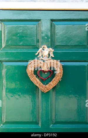 A forma di cuore ad ghirlanda di Natale appeso alla porta verde sotto ornati porta in ottone respingente a forma di L'Aquila Foto Stock