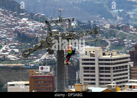 La Paz in Bolivia. Il 7 gennaio 2014. Un tecnico si arrampica su un pilone dove egli installerà una luce cavo sintetico che sarà trasportato in elicottero in posizione. Questa è la prima fase del processo di installazione finale del cavo in acciaio che portano le gondole per la nuova cabinovia / telecabina attualmente in costruzione per il collegamento delle città di La Paz e El Alto. Tre percorsi separati sono progettati come parte di un progetto ambizioso per alleviare la congestione del traffico. Il sistema è stato costruito dalla società austriaca Doppelmayr ad un costo di $234.6 milioni di euro finanziati dal governo boliviano. Foto Stock