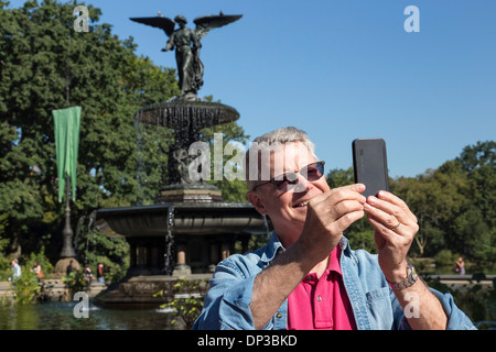 Senior uomo prendendo un Selfie con un dispositivo cellulare a Bethesda Plaza di New York Foto Stock