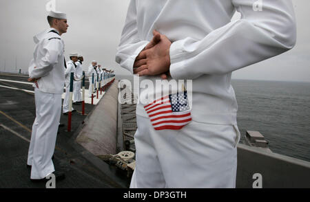 Jul 06, 2006; San Diego, CA, Stati Uniti d'America; con una bandiera americana nella sua tasca posteriore, US Navy Petty Officer di terza classe DANIEL BEACH a destra e sottufficiali di terza classe KEVIN ROBERTS, sinistra, insieme con gli altri il Museo della Portaerei U.S.S. Ronald Reagan il suo equipaggio la linea il ponte di volo della portaerei come si prepara ad entrare in San Diego Bay a conclusione della fanciulla 6 mese plus spiegamento operativo che Foto Stock